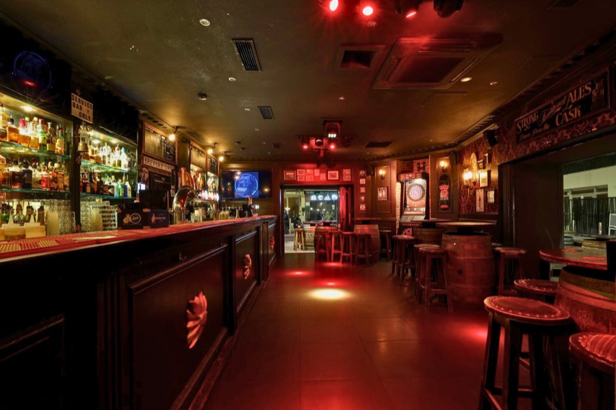 L'intérieur chaleureux du Barrel Pub, bois sombre et lumières tamisées.